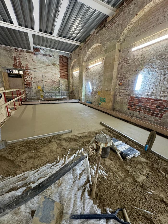 Laying limecrete with a straightedge in an arcaded brick hall